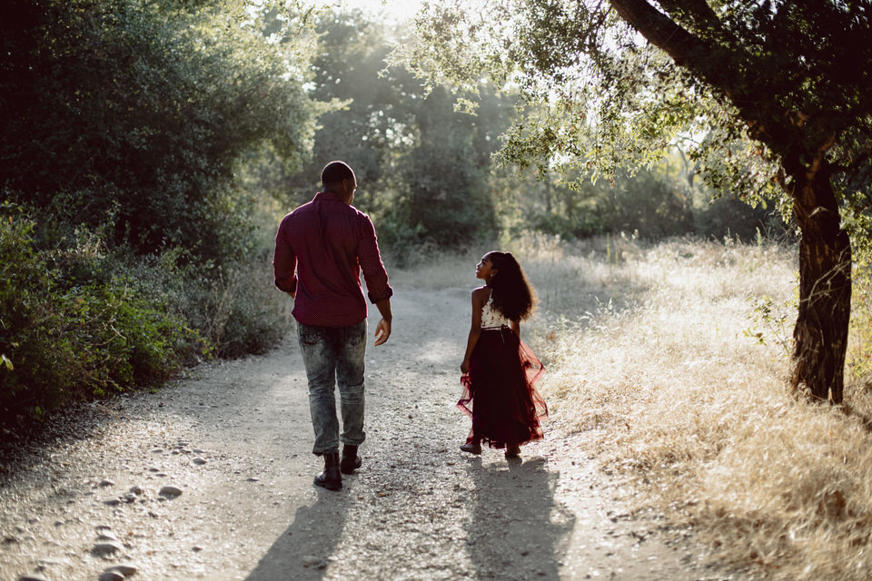 A father and daughter walking down a forest trail.