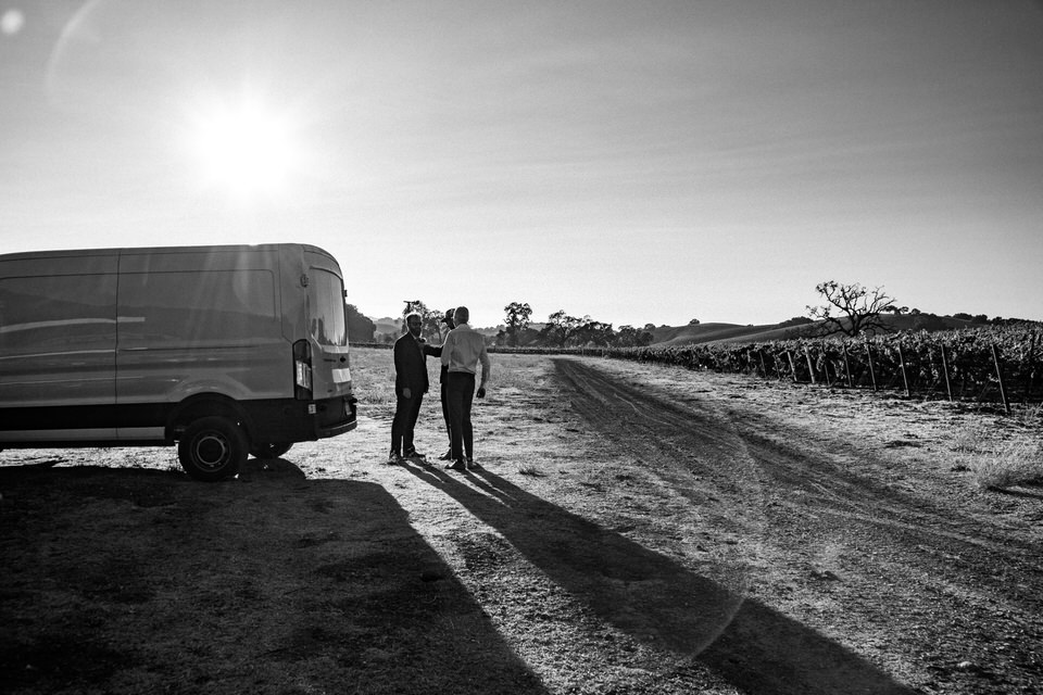 black and white image of the sun setting behind a white van