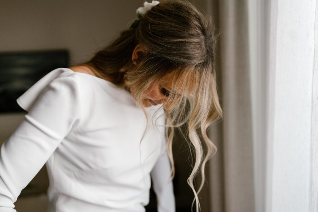 Bride getting ready in sunlit suite at The Pearl Hotel with mid-century decor and soft natural light.