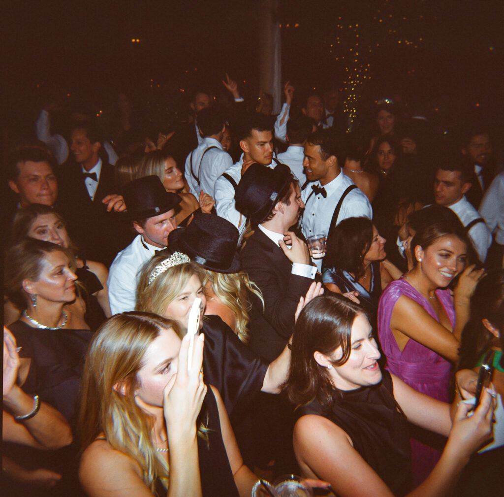 Group of wedding guests dancing together late night at Del Mar Country Club.