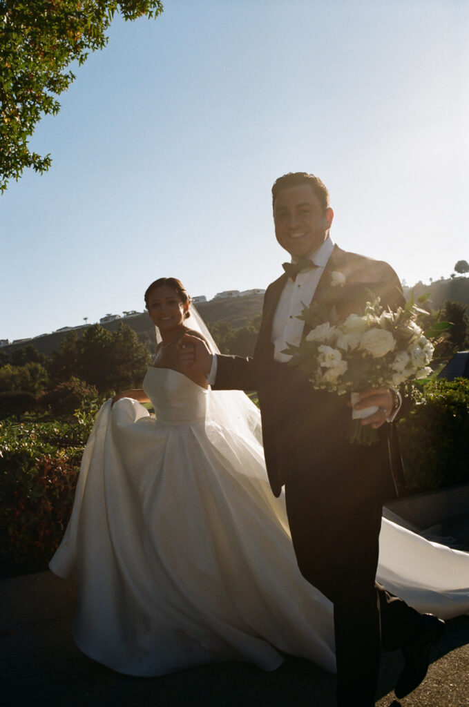 Bride and groom smiling in sunlight after ceremony at Del Mar Country Club.
