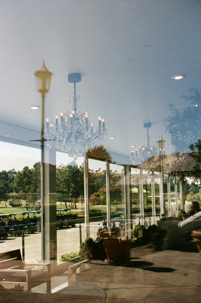 Reflection of chandeliers and outdoor patio view at Del Mar Country Club.