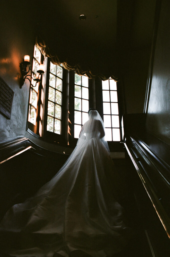 Bride walking up staircase with long veil flowing at Del Mar Country Club.