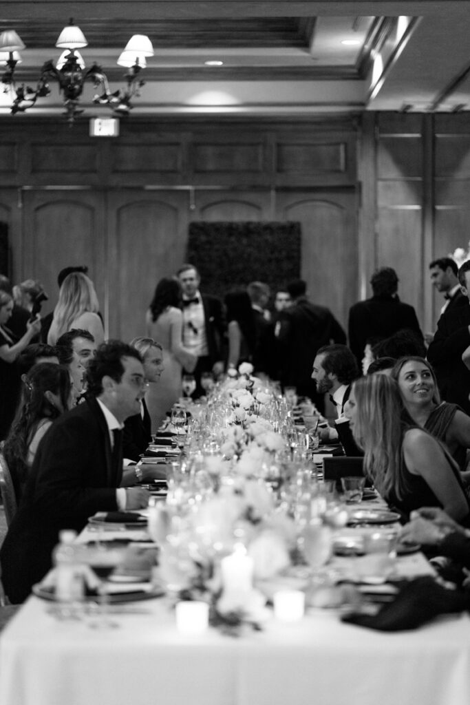 Black and white photo of guests seated at long dinner table during Del Mar Country Club wedding.