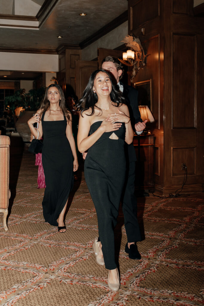 Bridesmaids walking into reception with drinks in hand at Del Mar Country Club.