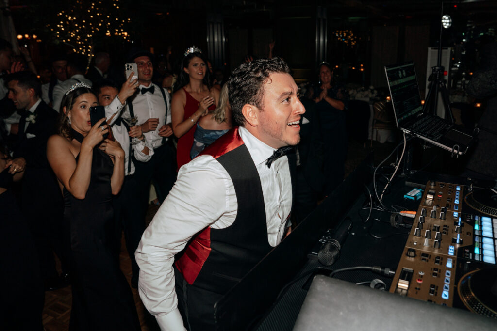DJ smiling while playing music for lively crowd at Del Mar Country Club reception.