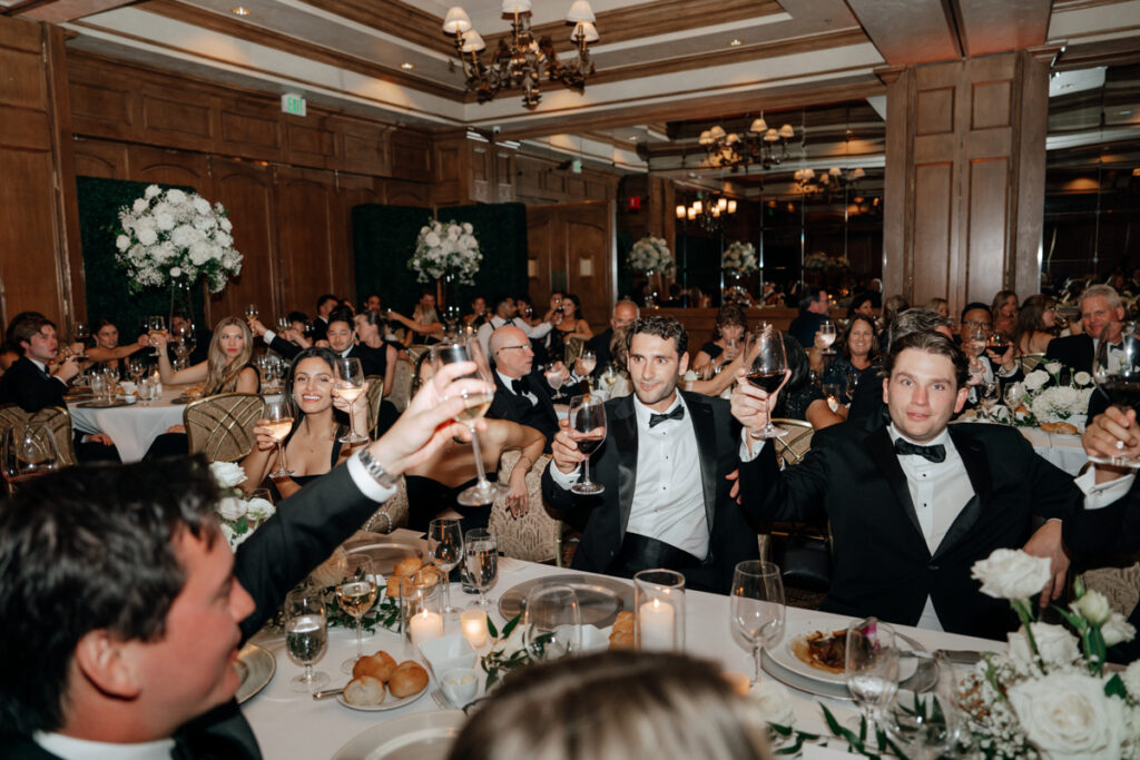Guests raising glasses during wedding toast at Del Mar Country Club reception.