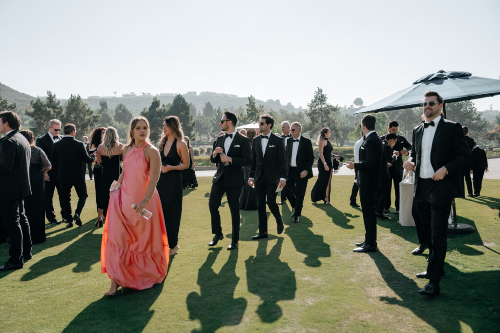 Guests walking across the greens in formal attire at Del Mar Country Club wedding.