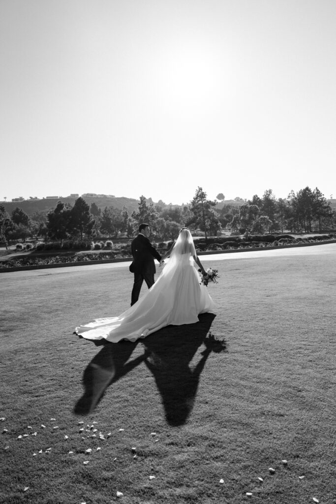 Black and white photo of bride walking arm in arm with escort down the aisle at Del Mar Country Club.