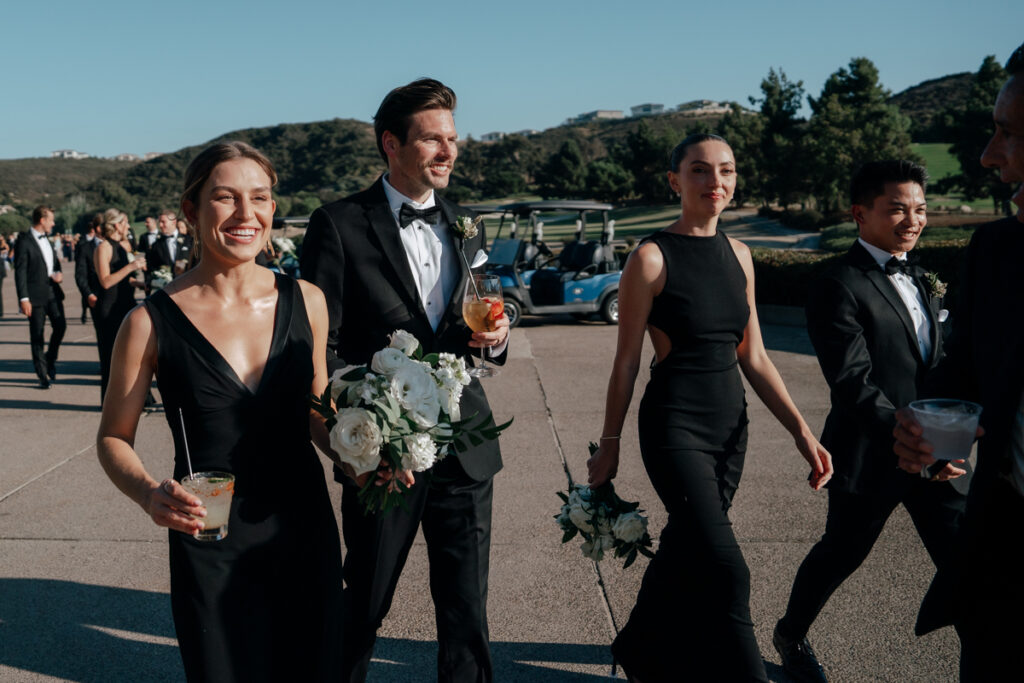 Wedding party smiling and walking outdoors at Del Mar Country Club.