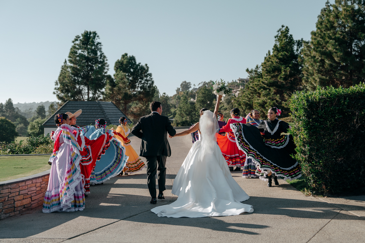 Bride and groom walking through Folklórico dancers in colorful dresses at Del Mar Country Club wedding