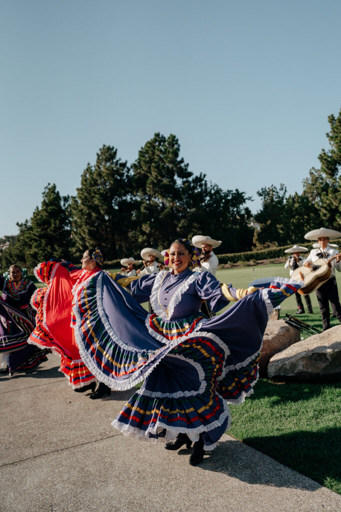 Group of Folklórico dancers spinning in traditional skirts at Del Mar Country Club wedding.