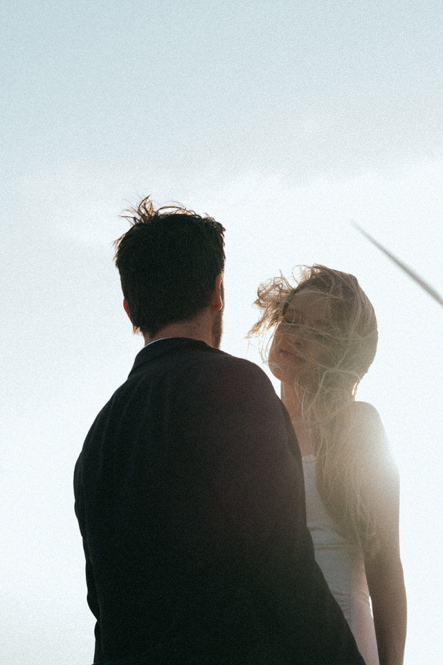 Backlit candid moment of couple with wind blowing hair at Palm Springs windmills