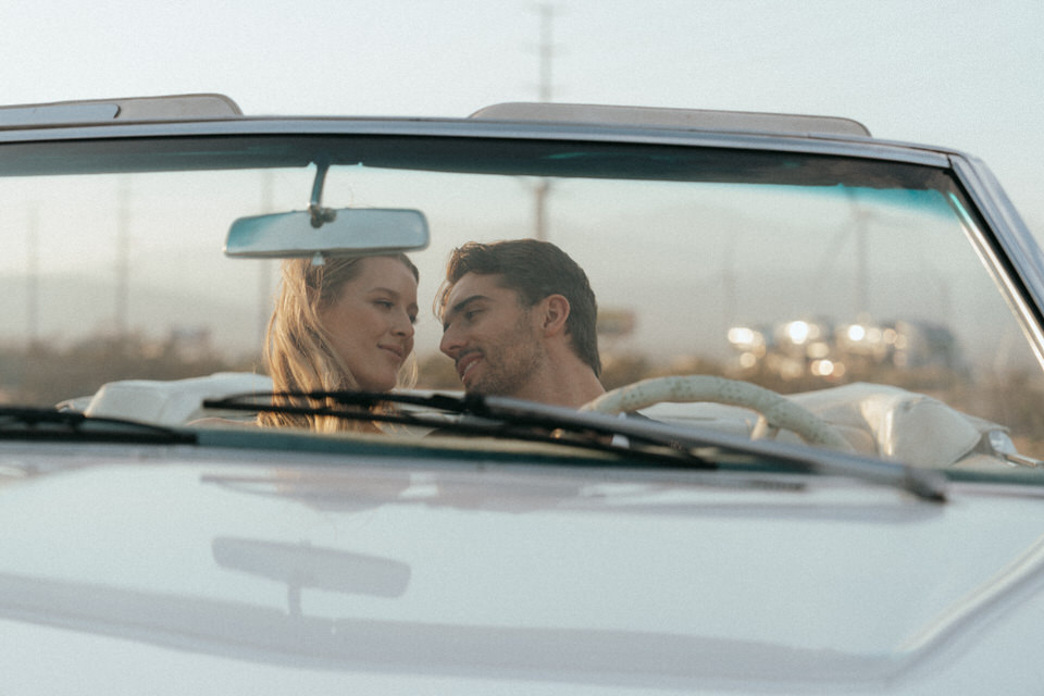 Bride and groom smiling at each other inside convertible car during desert wedding session