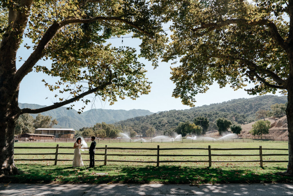 Wide shot of the sprinklers catching golden light behind the couple during the first look