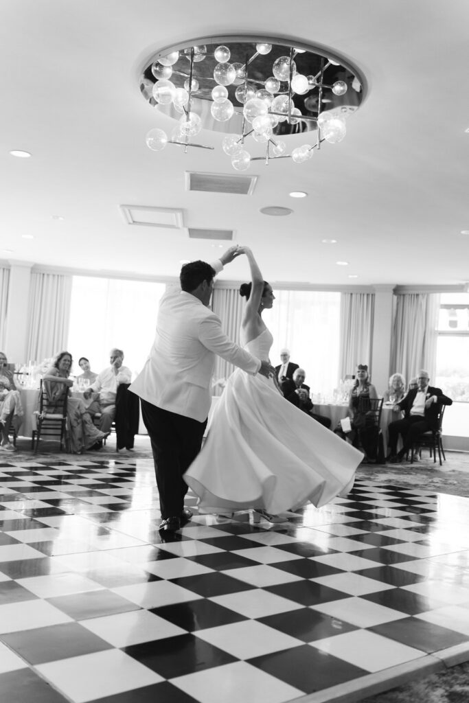 Hillary and Chris dancing on the checkered dance floor, motion blur, chandelier overhead