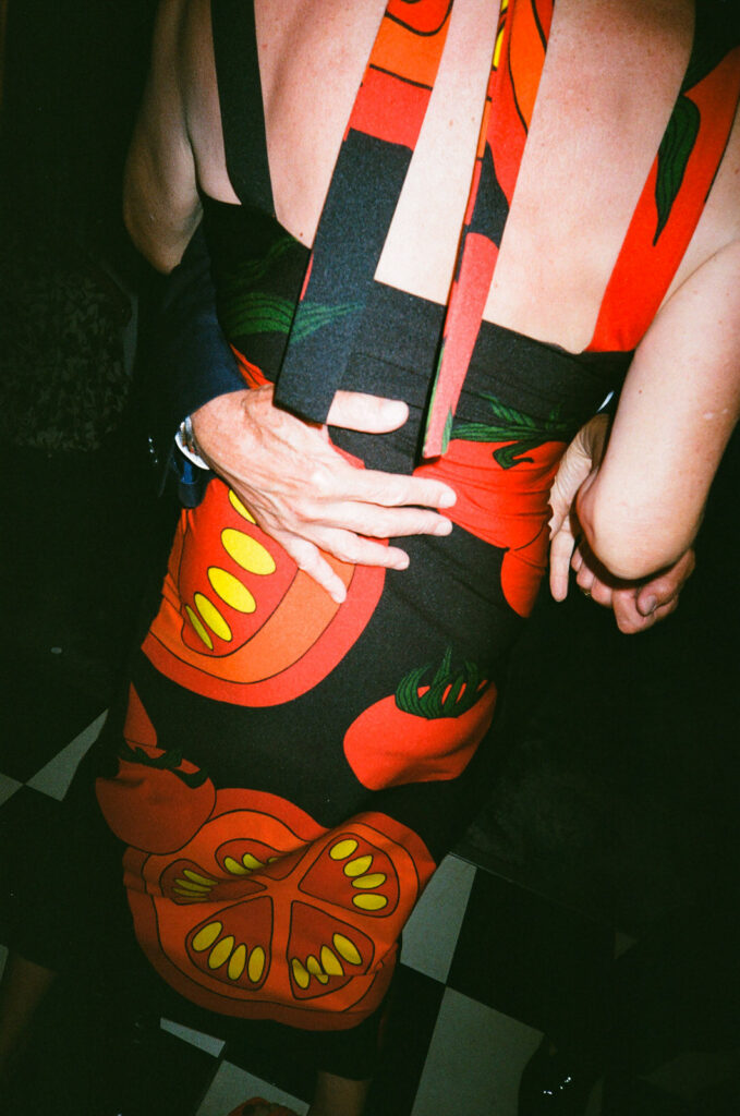 Close-up detail shot, of a mans hand around a woman's waist wearing a dress with slices of tomatoes on it