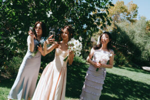 Bridesmaids in pastel dresses taking photos together before the ceremony