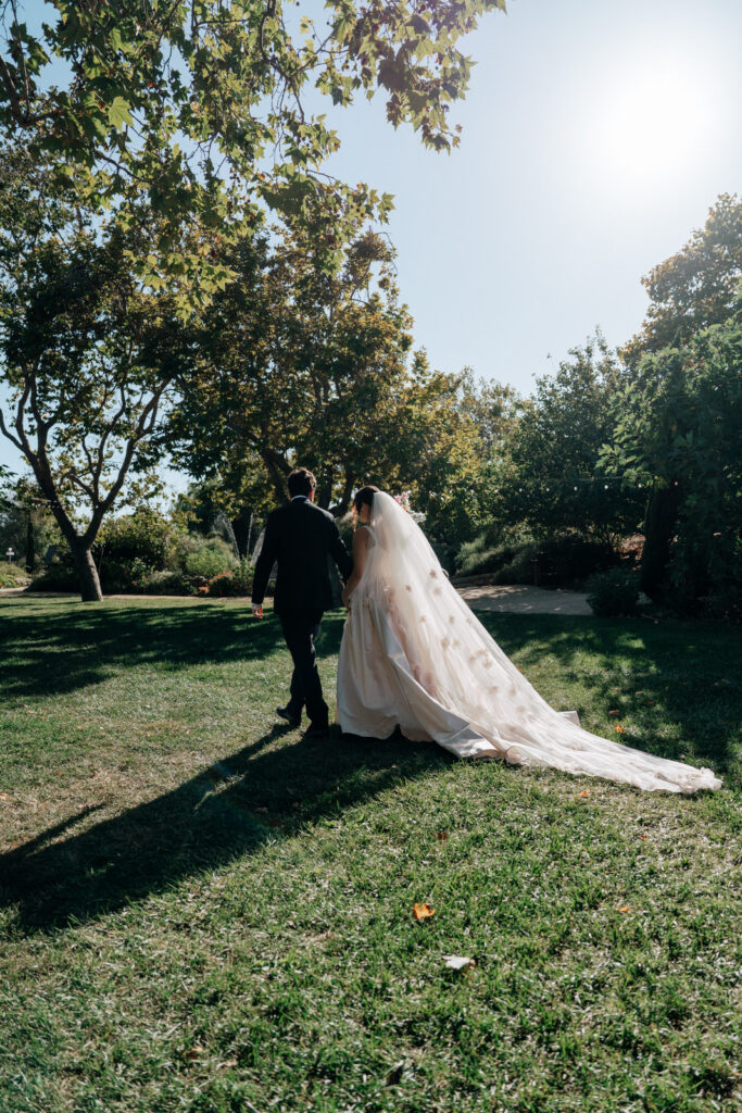 Bride and groom walking hand in hand across the grass after the ceremony